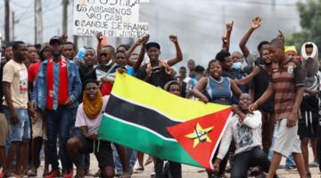 Youth pose behind a Mozambique flag 